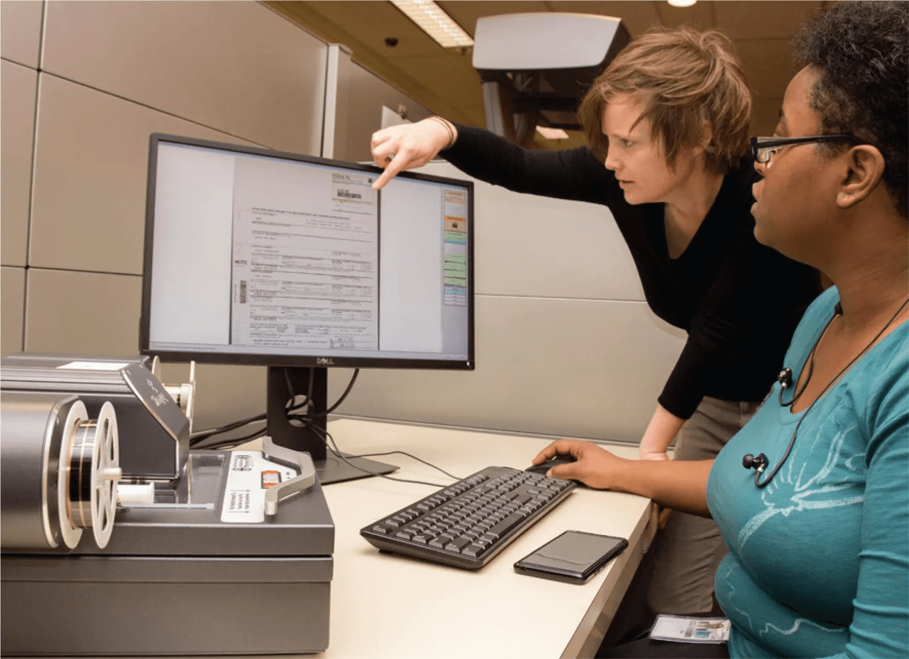 Two librarians reviewing a digital archive record together