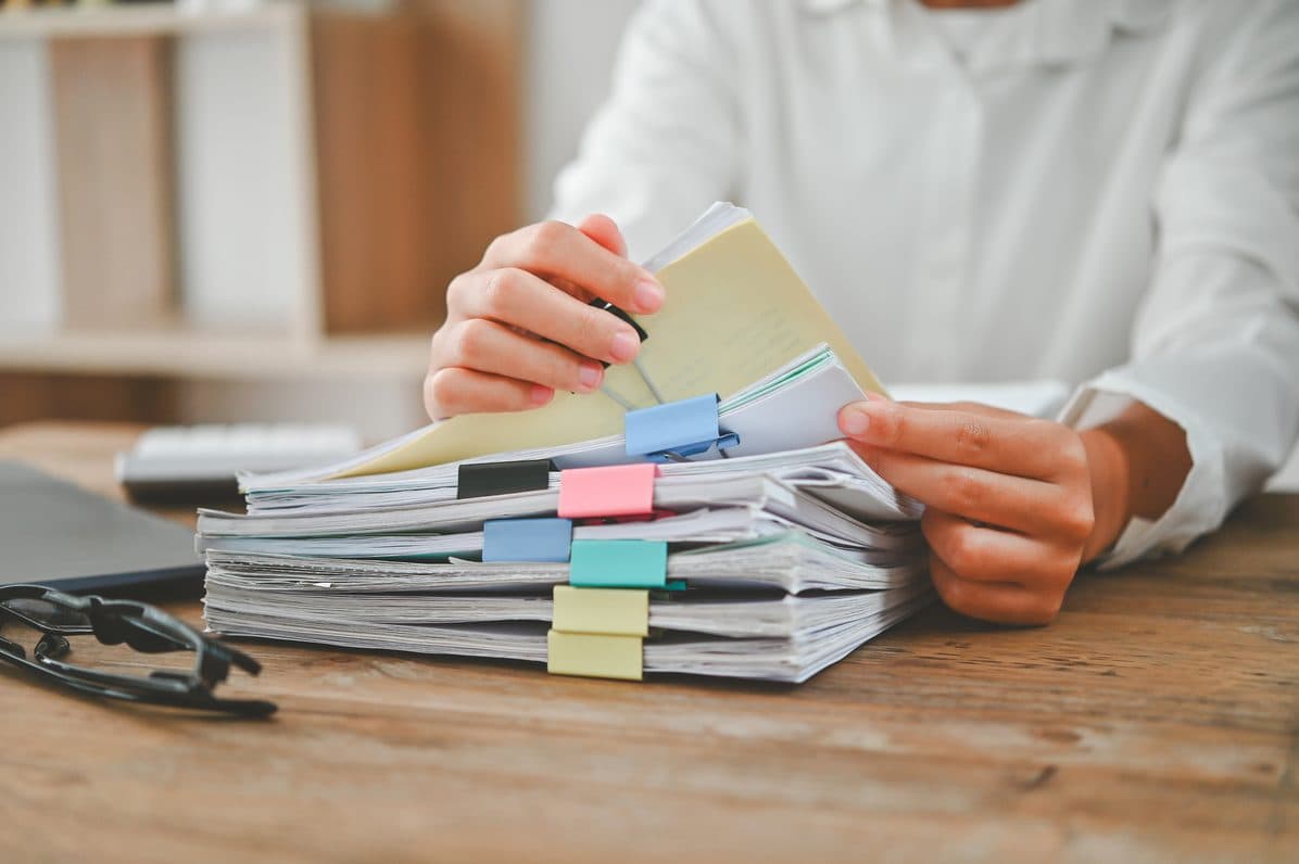 An archivist sorting through a stack of tabbed paper records